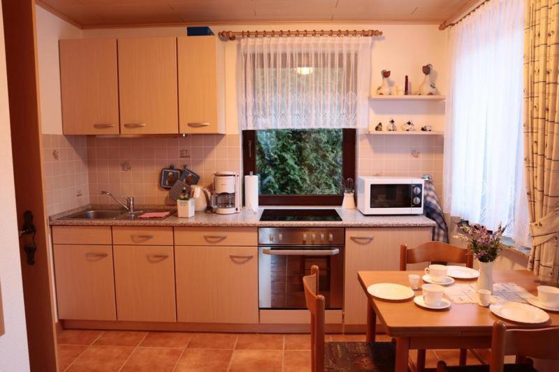 a kitchen with a table and a microwave and a table and chairs at Ferienhaus Utspannen in Prerow