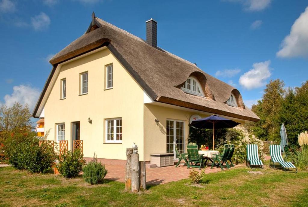 ein Haus mit einem Strohdach, einem Tisch und Stühlen in der Unterkunft Krabbenort 1 - 6b in Prerow