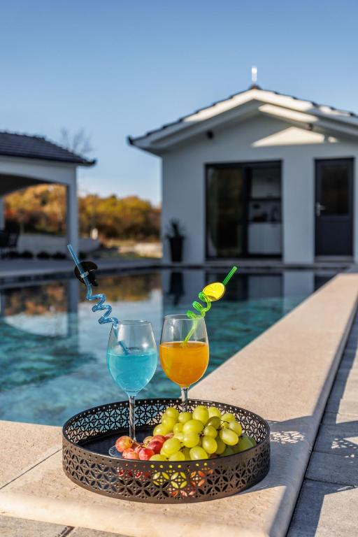 a tray of fruit and drinks on a table near a pool at Villa Vilma-house with heated pool & garden in Trilj