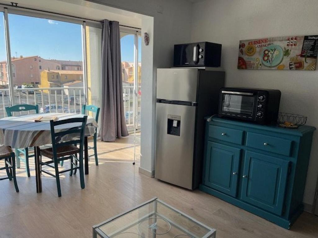 Il comprend une cuisine équipée d'une table, d'un réfrigérateur, d'une table et de chaises. dans l'établissement Magnifique T3 rénové pour 4 pers. à Agde, proche plage, parking privé - FR-1-749-58, au Cap d'Agde