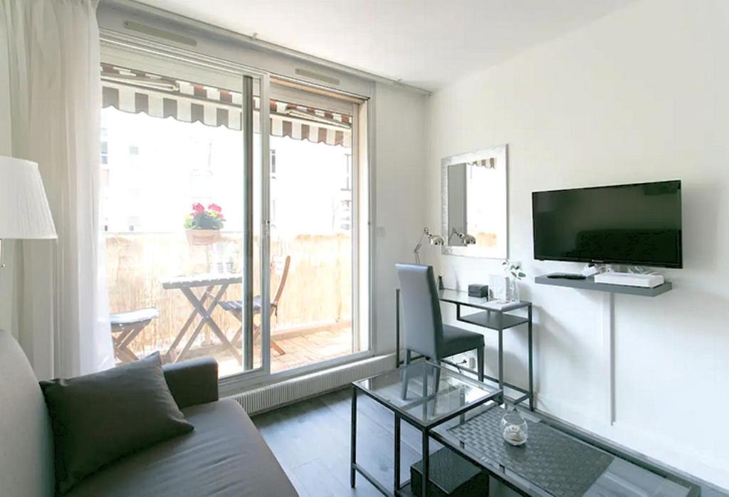 un salon avec un canapé et une grande fenêtre dans l'établissement Appartement charmant proche Montparnasse, à Paris