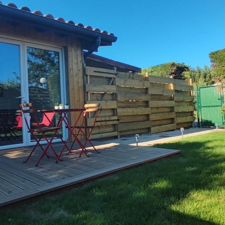 une table et des chaises sur une terrasse à côté d'une clôture dans l'établissement A 10 minutes des plus belles plages landaises, charmant T2 avec jardin privatif, à Angresse