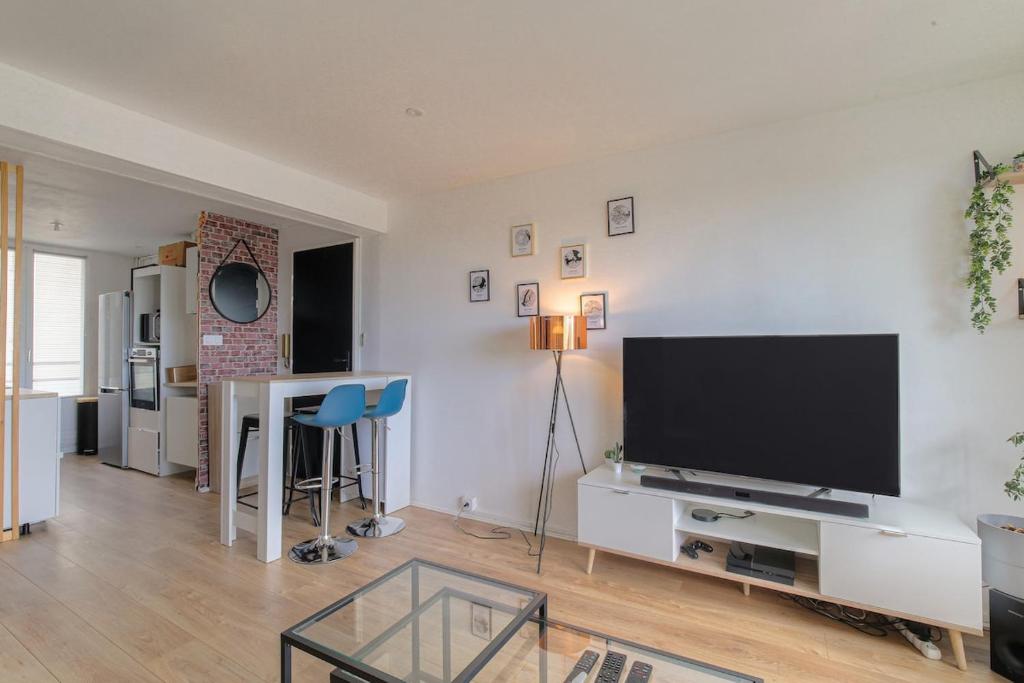 a living room with a large flat screen tv at L'Escale, Appartement 2 chambres avec Balcon, Villefranche in Villefranche-sur-Saône