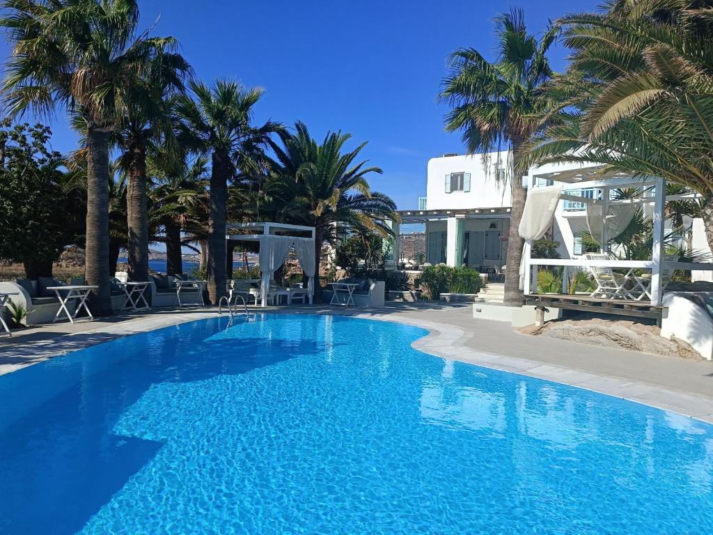 a swimming pool with palm trees and a building at Zephyros in Paraga
