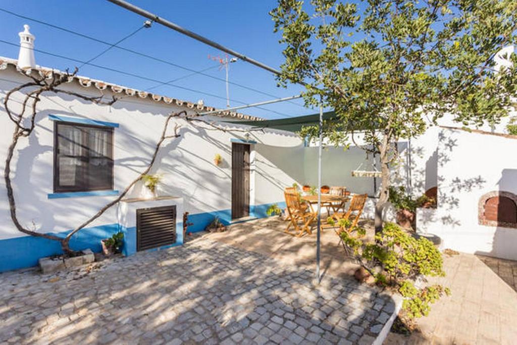a patio of a house with a table and chairs at Charming Cottage near Tavira in Juliãos