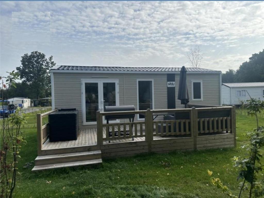 a mobile home with a wooden deck with a grill at Huis Meerwijck in Gasselte