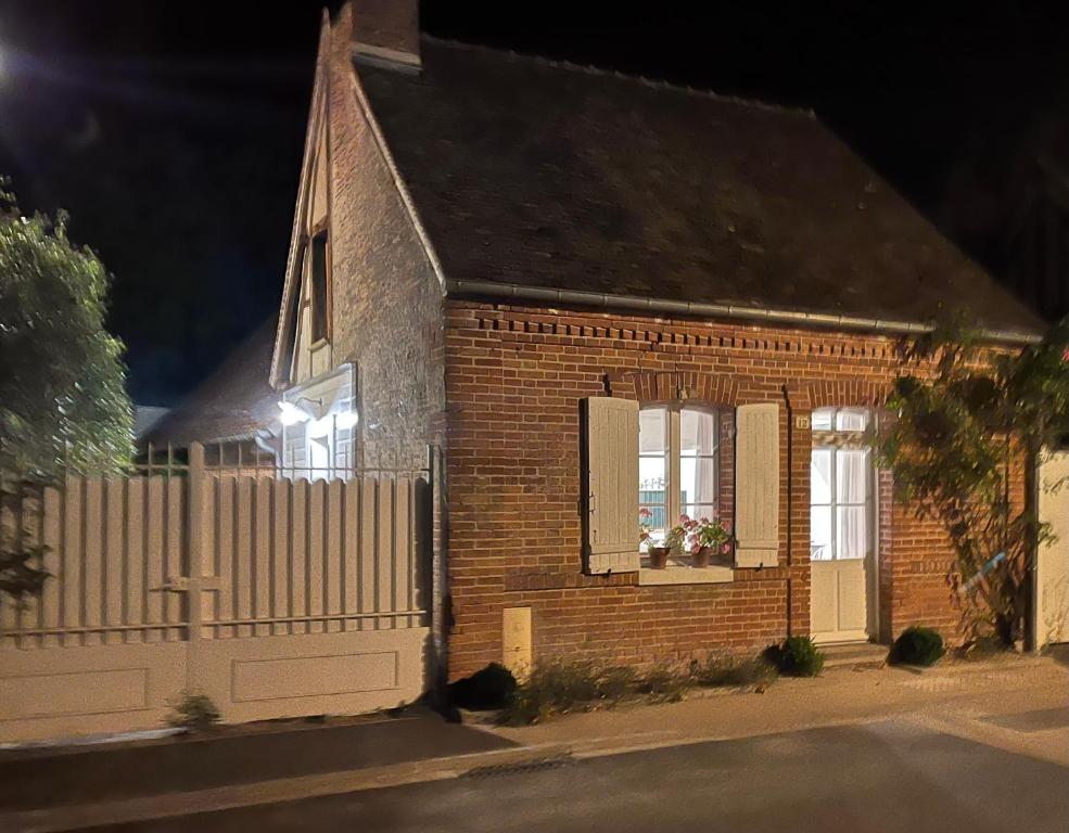a brick house with a white fence and a window at La petite maison in Souvigny-en-Sologne
