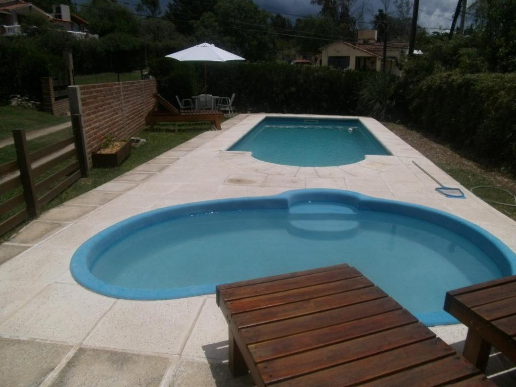 einen großen blauen Pool mit einer Bank und einem Tisch in der Unterkunft Cabañas Tio Willy in Villa Carlos Paz