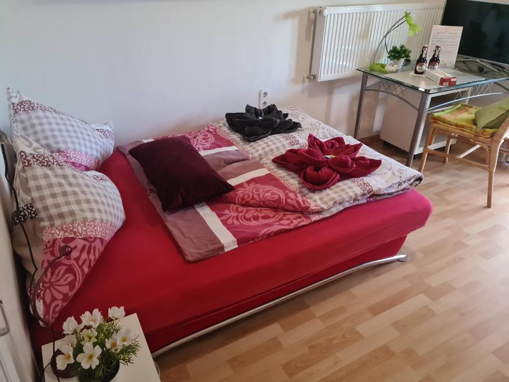 divano rosso in camera con tavolo di Ferienwohnungen wie im Süden Großostheim a Großostheim