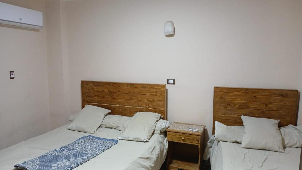 twee bedden in een slaapkamer met houten hoofdeinden bij siwa shaly hostel 3 in Siwa