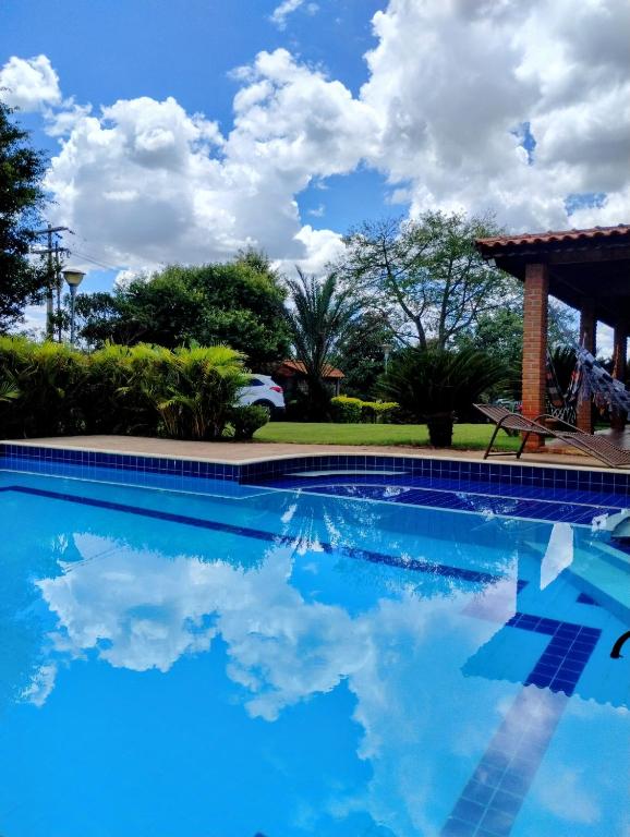 a swimming pool with a blue sky and clouds at Recanto da Família in Quadra