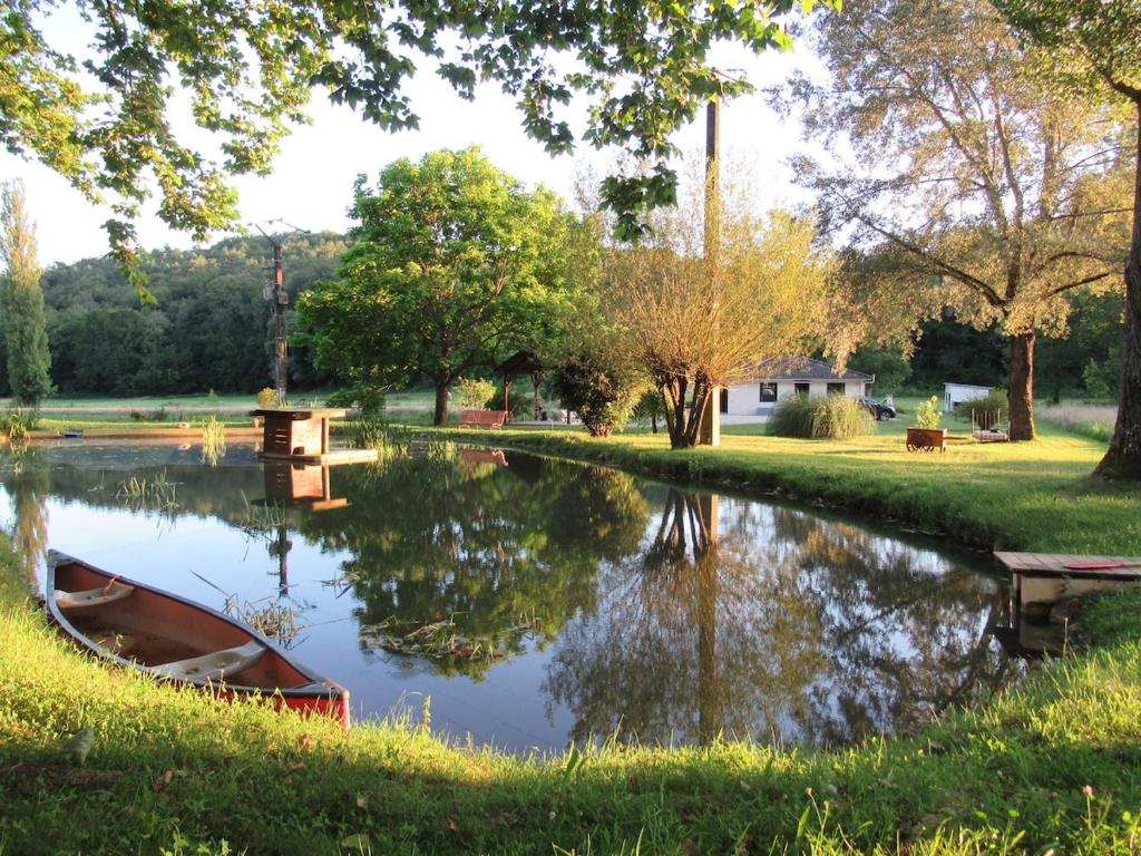 un bateau assis sur l'herbe à côté d'une rivière dans l'établissement Un havre de paix en Périgord, à Fanlac