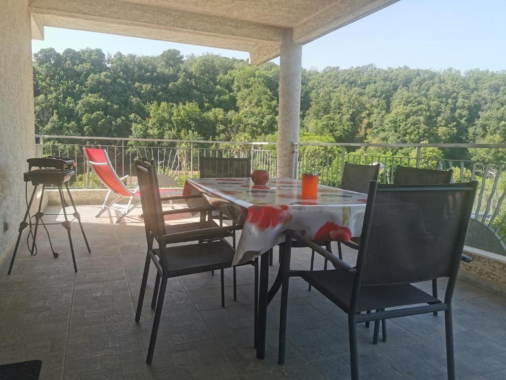 Une table à manger et des chaises sont disponibles sur la terrasse. dans l'établissement Appartement traversant, à Folelli