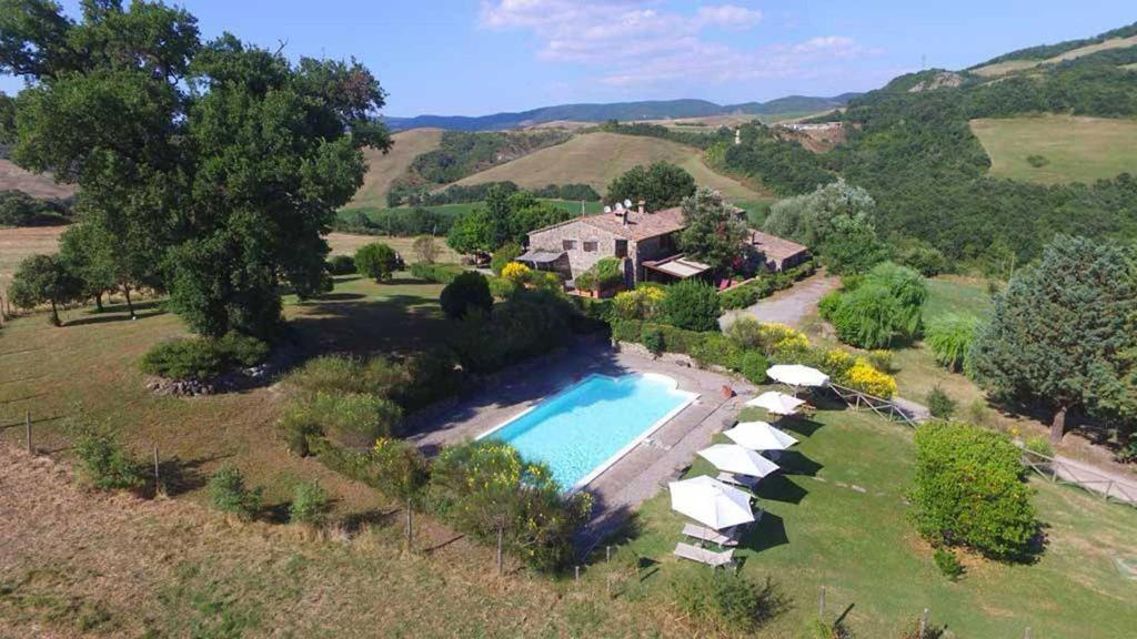 una vista aérea de una casa con piscina y sombrillas en Cottage Le Ginestre con piscina in Val d'Orcia, en Radicofani
