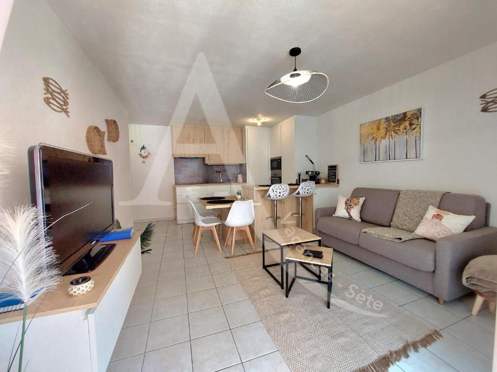 un salon avec un canapé et une table dans l'établissement T3 renove dans residence avec piscine et garage Capacite max 6 personnes, à Sète