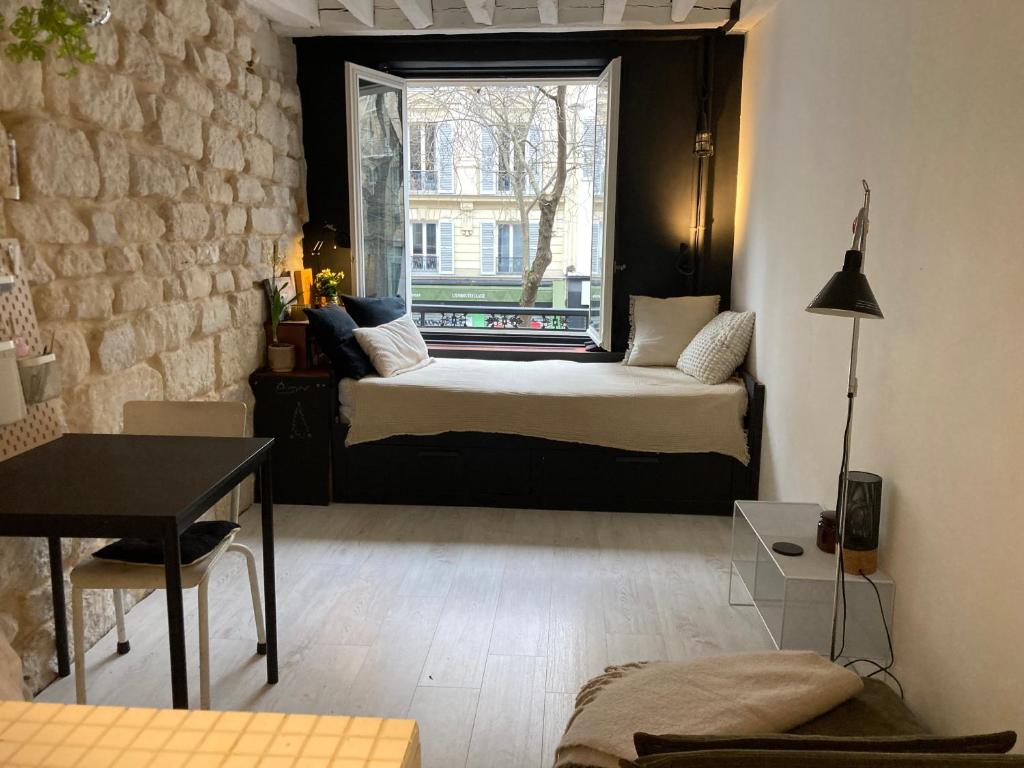 une petite pièce avec un lit et une fenêtre dans l'établissement Charmant studio près du Marais, à Paris
