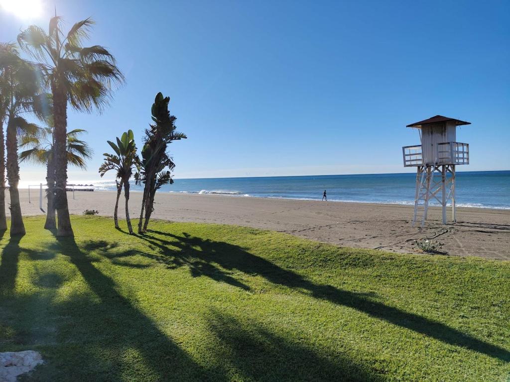 a view of a beach with palm trees and a lifeguard tower at Hikari&Sineida Home in Rincón de la Victoria