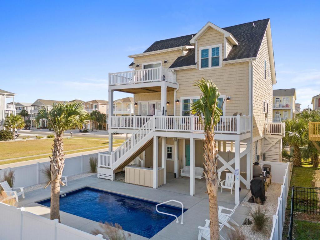 a house with a swimming pool and palm trees at Experience luxury at Notorious OIB, a spacious 4 bedrooms, 4 baths, perfect for up to 10 guests in Ocean Isle Beach