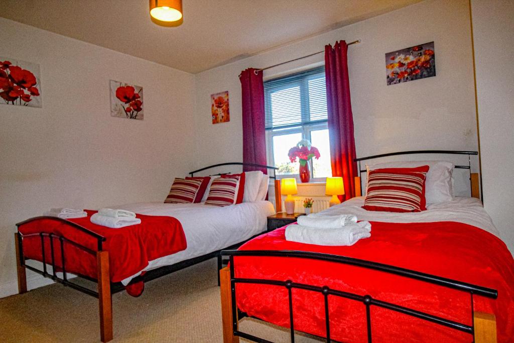 2 camas en un dormitorio con cortinas rojas y ventana en Ripley House by Smart Corporate Stays, en Ripley