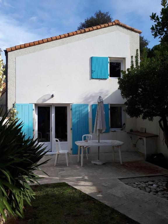 une maison blanche avec des volets bleus et une table dans l'établissement Detente et confort proche de la mer, à Saint-Trojan-les-Bains