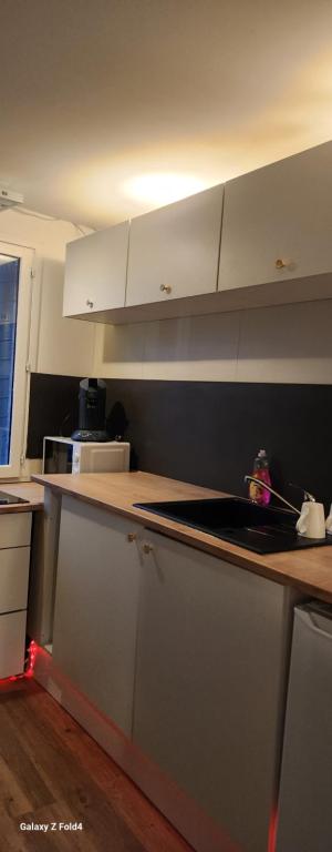 Una cocina con gabinetes blancos y encimera. en Location t2, en Lannoy