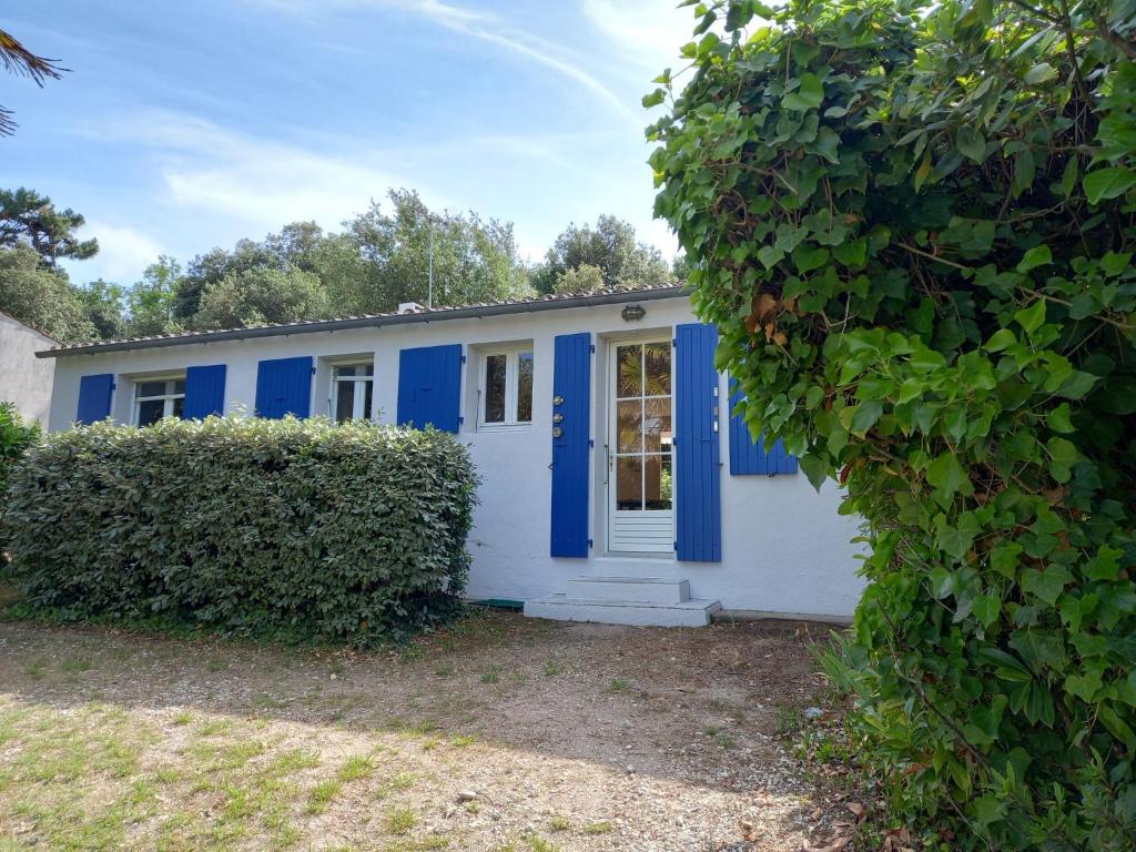 une maison avec des portes bleues et une haie dans l'établissement Maison avec terrasse à Vert Bois, à Dolus-d'Oléron