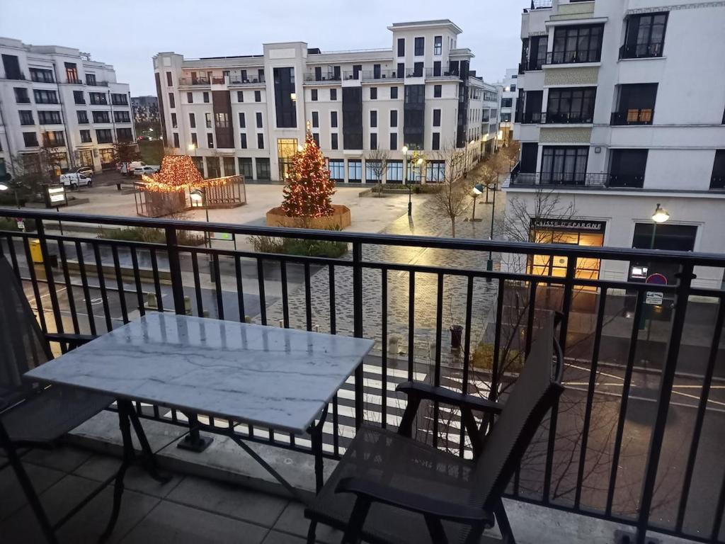 une table et des chaises sur un balcon avec un arbre de Noël dans l'établissement Charmant Appartement Disneyland, à Chessy
