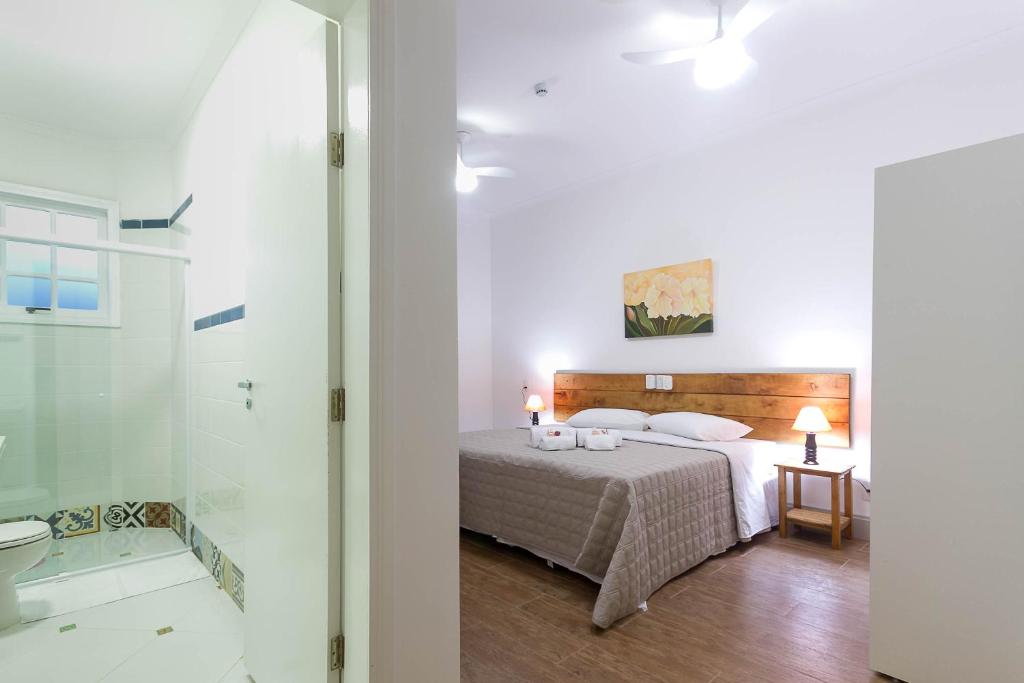 a bedroom with a bed and a bathroom with a shower at Sagrados Corações - Pousada in Pindamonhangaba