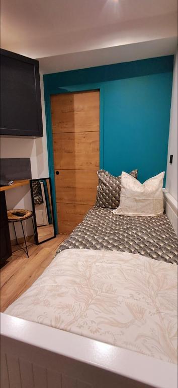 une chambre avec un grand lit avec un mur bleu dans l'établissement Gardam hyper centre cathédrale, à Reims