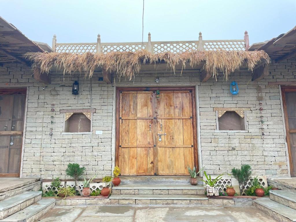 a house with a wooden door and a thatch roof at Virasat homestay in Chanderi