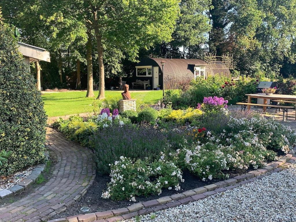 a garden with flowers and a table and a bench at Tinyhouse in Bakkeveen in Bakkeveen
