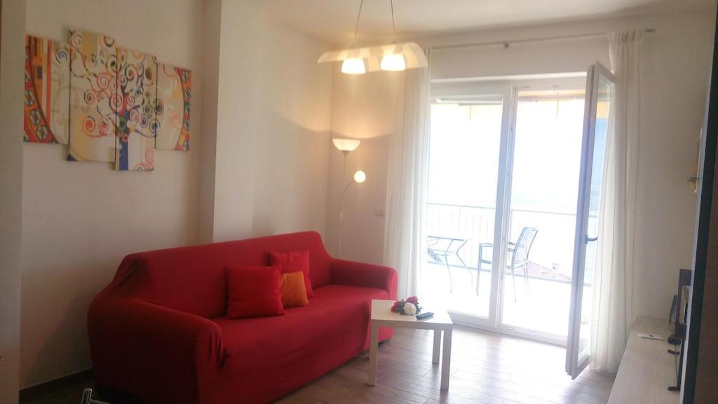a living room with a red couch and a sliding glass door at Casa bella vista Emma lago Como in Vercana
