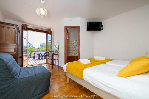 a bedroom with a bed and a couch and a balcony at Auberge du Point Sublime in Rougon