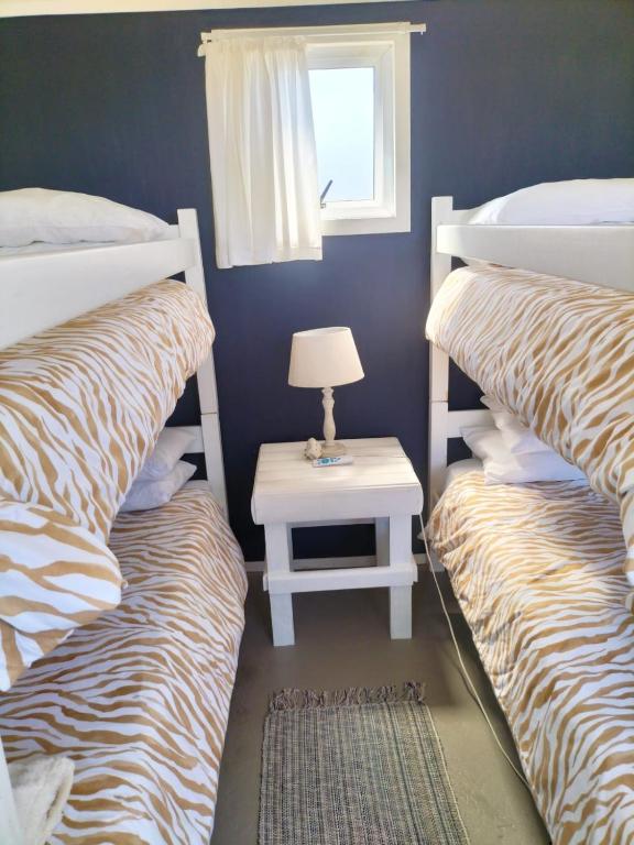 a bedroom with two bunk beds and a table with a lamp at Townsend Backpackers in Lambertʼs Bay