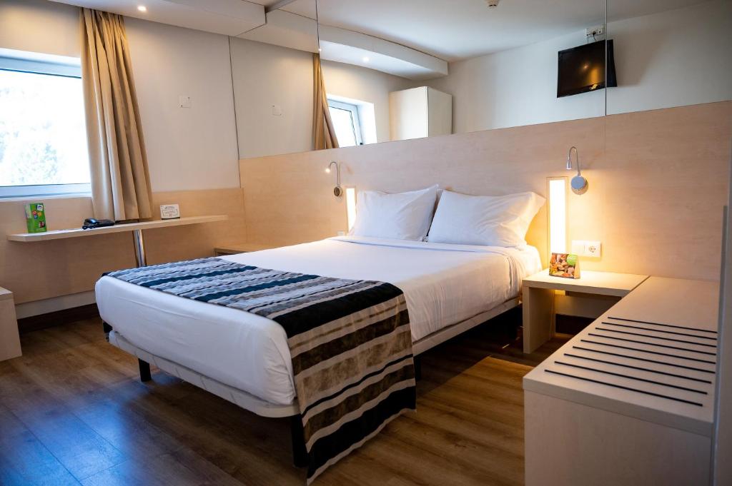 a hotel room with a large bed and a desk at Park Hotel Porto Aeroporto in Maia