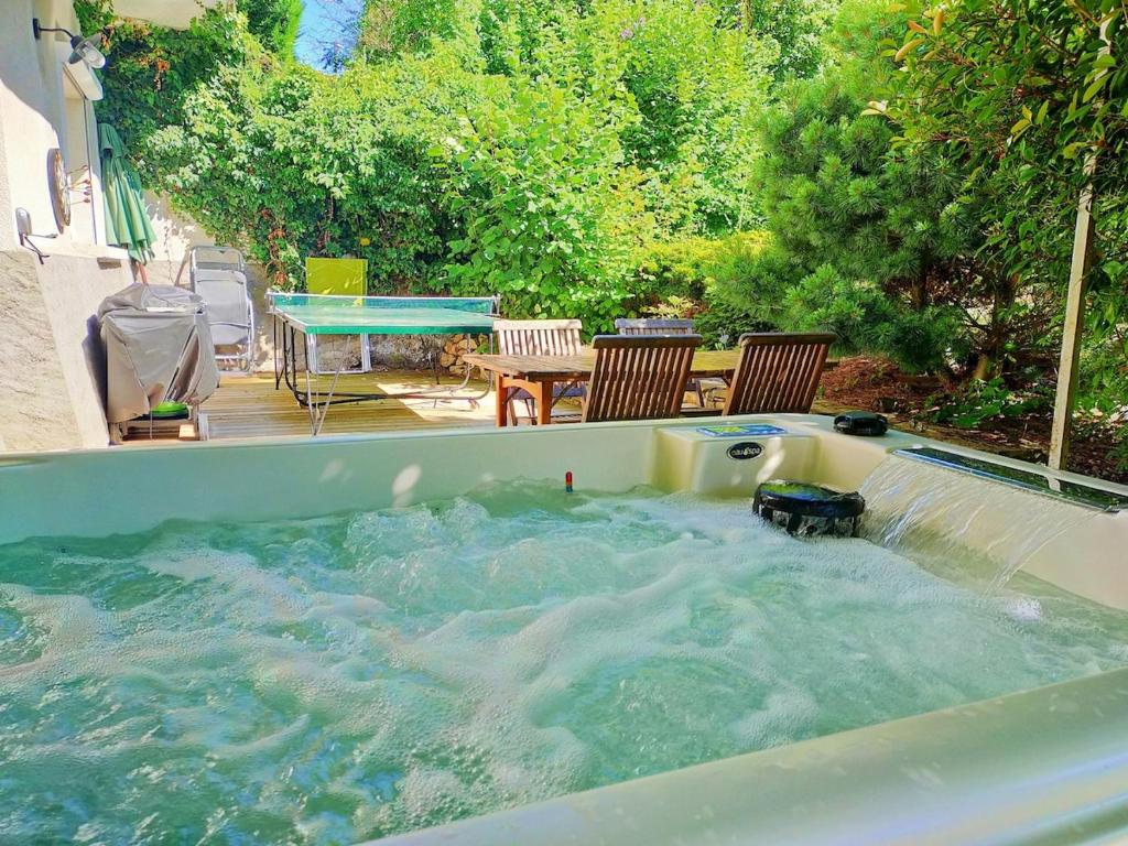 a hot tub in a backyard with a table and chairs at Magnifiques voûtes avec SPA in Saint-Amant-Tallende