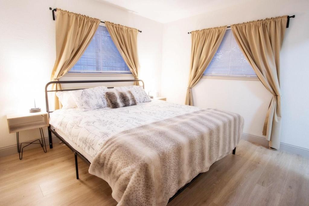 1 cama en un dormitorio con 2 ventanas grandes en Beautiful Family Home Mins to Lackland, en San Antonio
