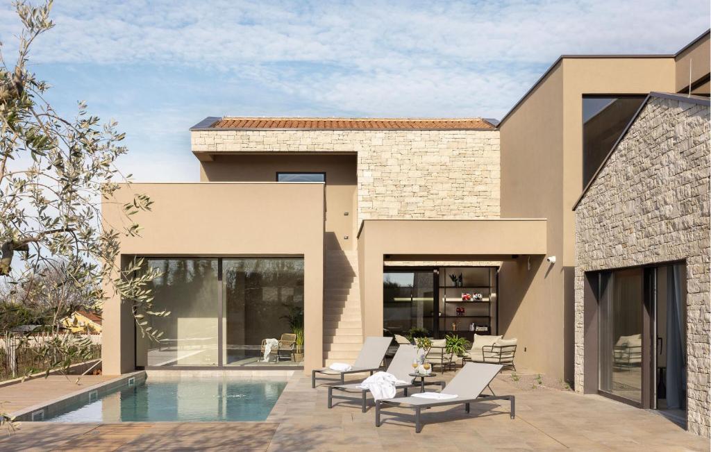 a house with a swimming pool and lounge chairs at Stunning Home In Kastelir With Sauna in Kaštelir