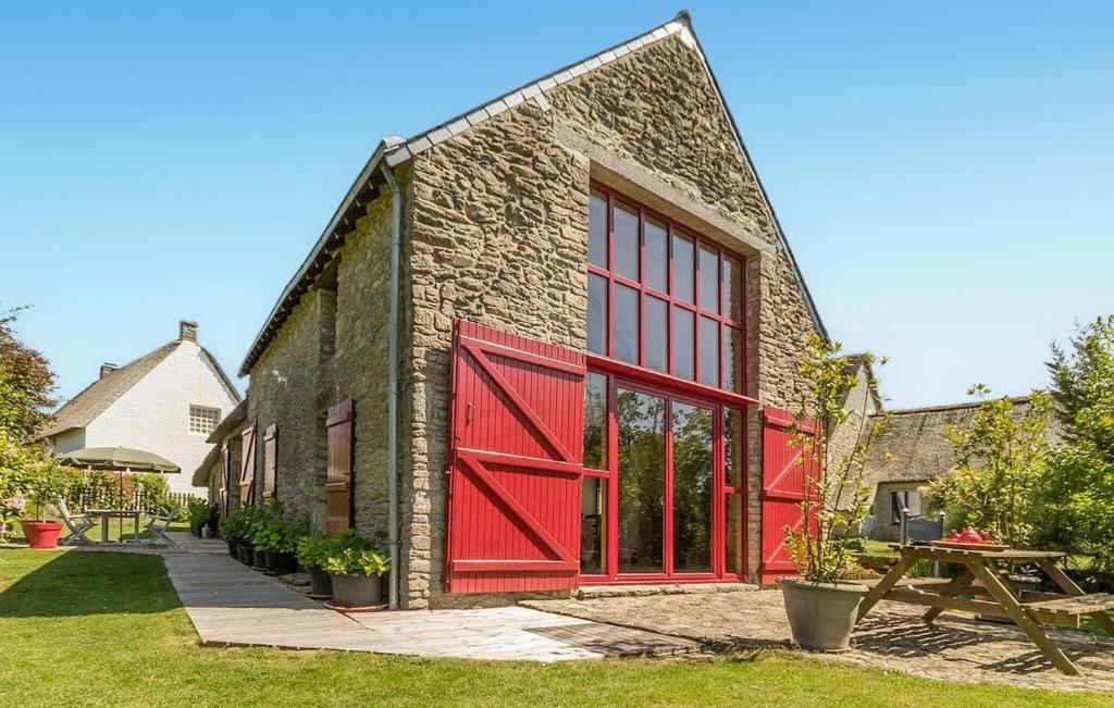 - un bâtiment en briques avec des portes rouges et une table de pique-nique dans l'établissement Cozy Home In Saint Lyphard With Wifi, à Saint-Lyphard