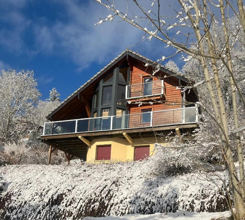 une maison sur une colline avec de la neige au sol dans l'établissement Chalet chaleureux à Basse-sur-le-Rupt, vue montagne superbe, à Basse-sur-le-Rupt