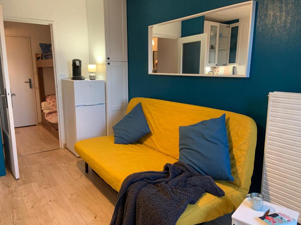 - un canapé jaune avec des oreillers bleus dans le salon dans l'établissement Studio pieds des pistes les orres 1650, aux Orres