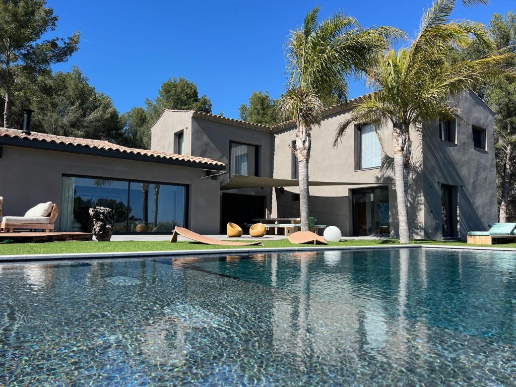 une piscine devant une maison avec des palmiers dans l'établissement Villa Bellysouh, à Sanary-sur-Mer