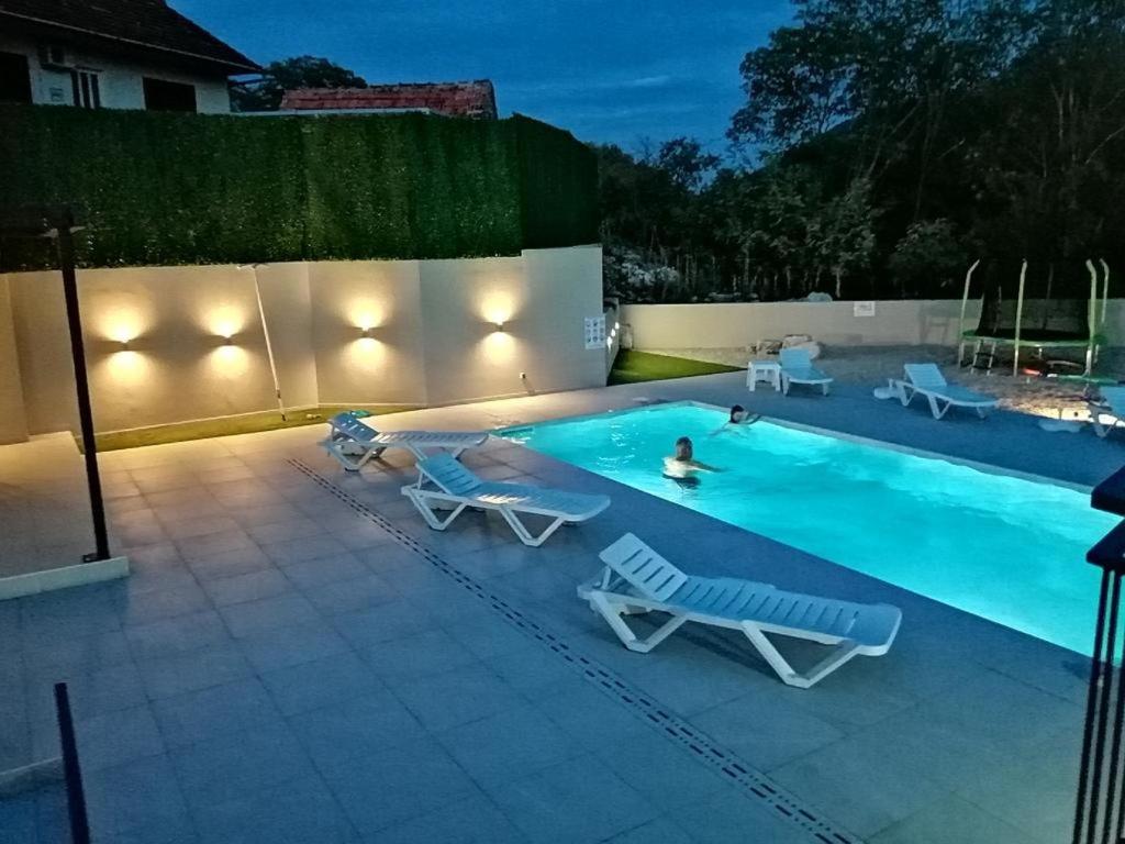 a swimming pool with lounge chairs and a person swimming at House Mande i Kate in Vrgorac