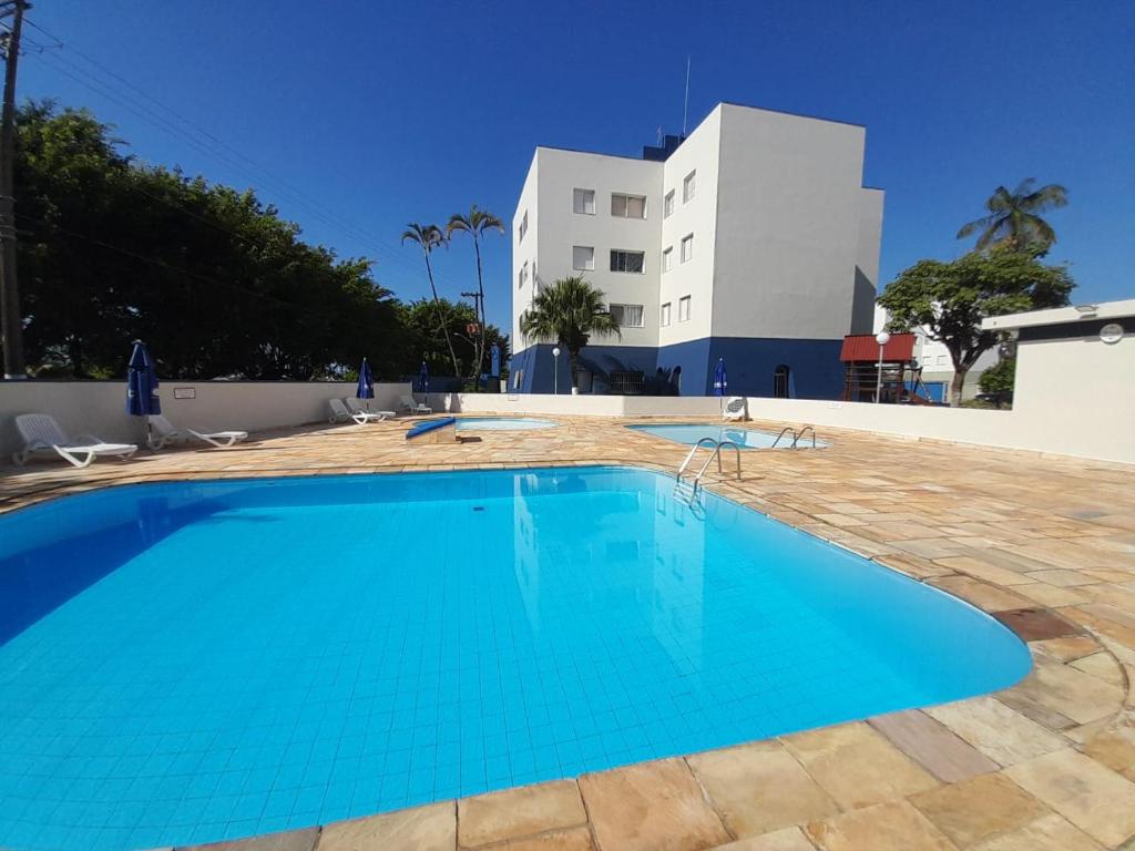 a swimming pool in front of a building at Apartamento com piscina à 1km da praia in Caraguatatuba