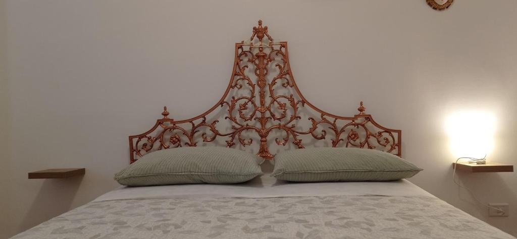 un letto con testiera in legno e 2 cuscini di Appartamento Levante a Bari