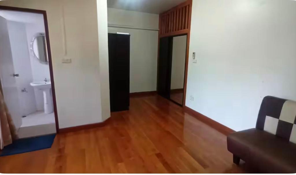Una sala de estar con un sofá y suelo de madera. en Rachaprorob condo, en Bangkok