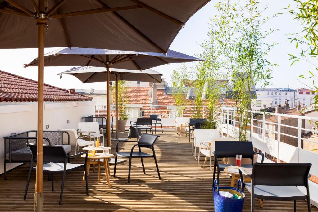 a patio area with chairs, tables and umbrellas at Okko Hotels Cannes Centre in Cannes