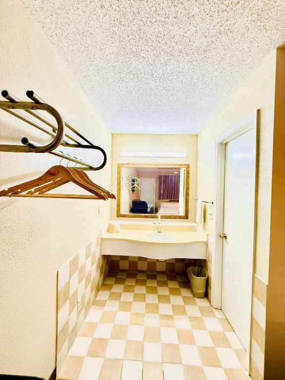 a bathroom with a tub and a checkered floor at Travelodge by Wyndham-Thomasville AL in Thomasville