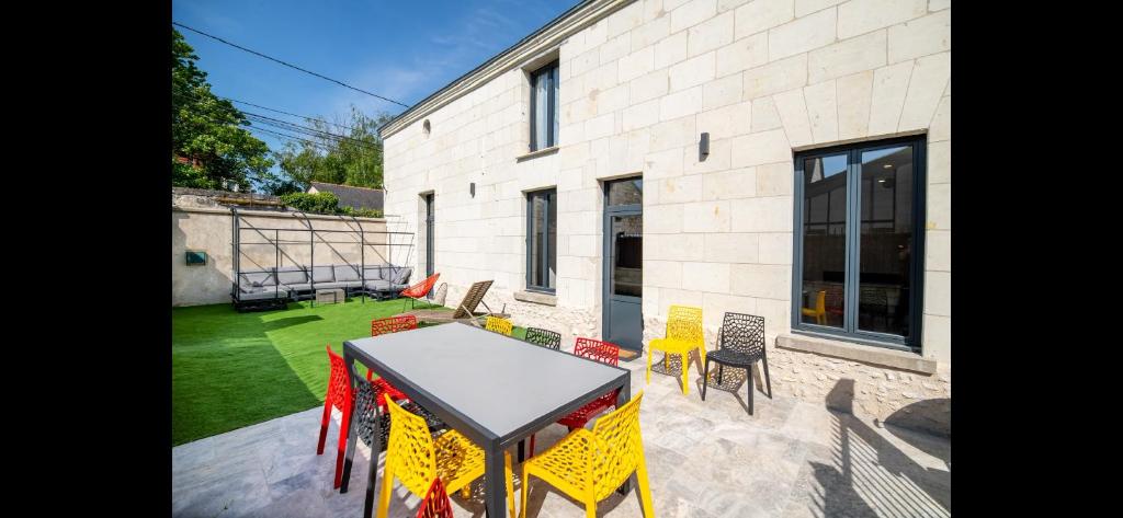 un patio avec une table et des chaises devant un bâtiment dans l'établissement Gîte La Troglo, à Varrains