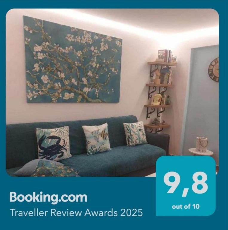 a living room with a blue couch and a painting at Colorful House Tsoutsouras in Tsoutsouros